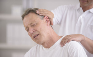 Mężczyzna z osteochondrozą szyi na przyjęciu ręcznego masażysty